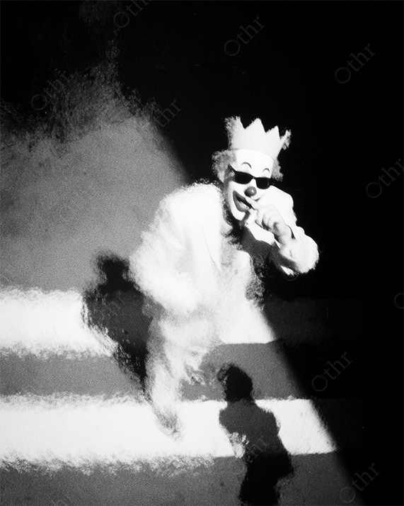 Clown Wearing Crown and Sunglasses Projected on Striped Pedestrian Crossing