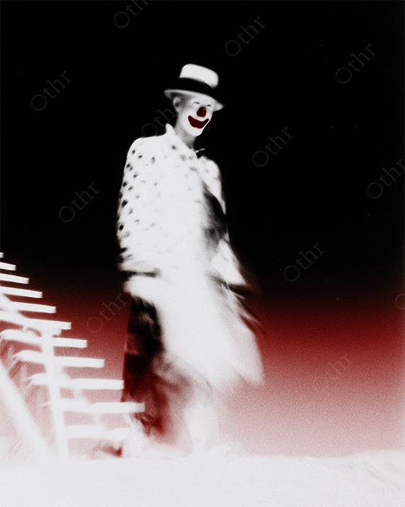 Blurry Clown with Hat and Red Nose Standing Beside White Ladder Against Red Gradient Background