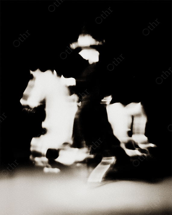 Blurry Silhouette of Cowboy on Horseback in Motion Against Dark Background – Monochrome