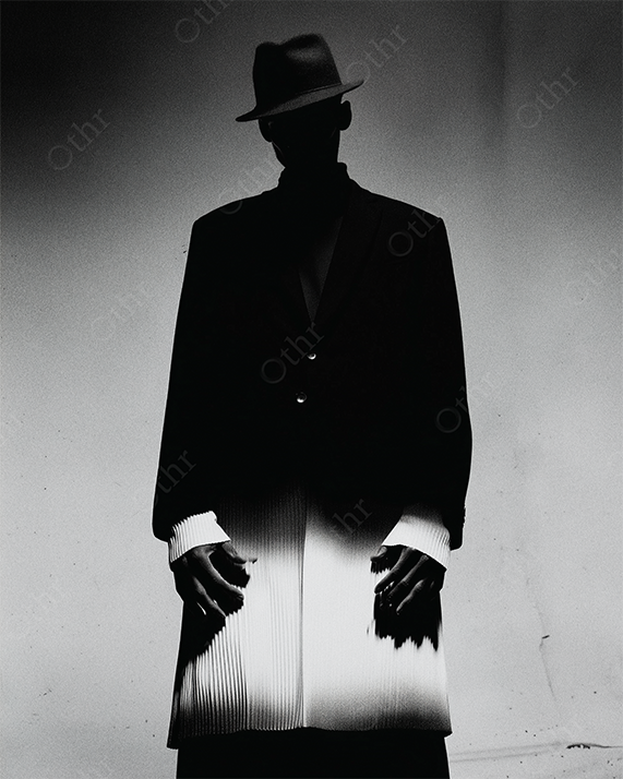 Shadowed Figure in Gradient Trench Coat and Fedora Standing in Studio Light – Monochrome