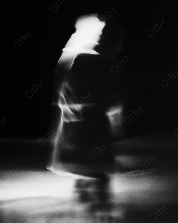 Abstract Blurred Figure in Motion Against Black Background with Soft Light Trails – Monochrome