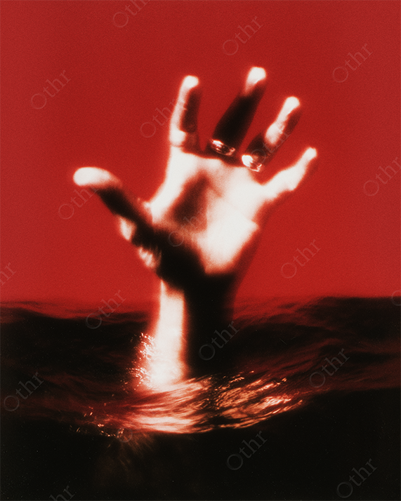 Outstretched Hand with Rings Emerging From Water Against Red Background – Soft Focus