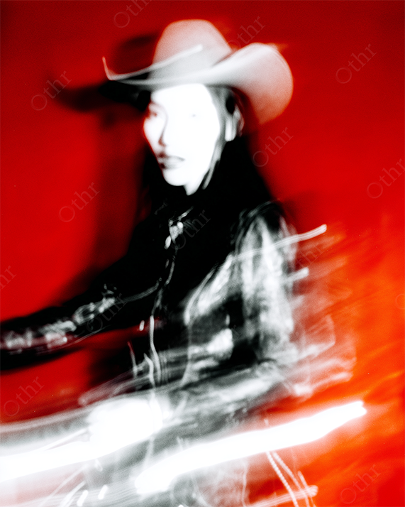Blurry Portrait of Woman in Cowboy Hat and Leather Jacket Against Red Background – Motion Blur