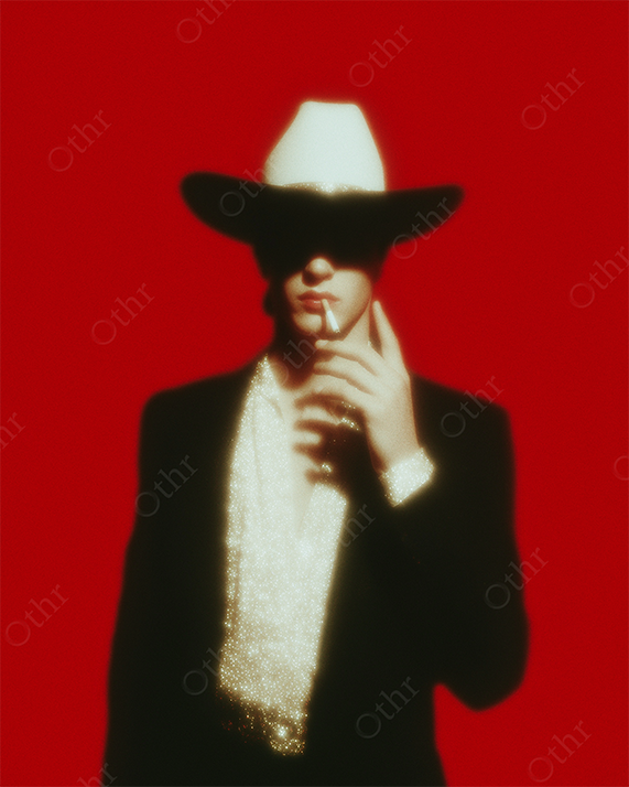 Man in Cowboy Hat and Glittering Shirt Smoking Against Red Background – Soft Glow