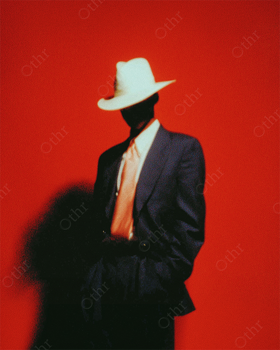 Silhouetted Figure in Suit and White Hat Against Red Background
