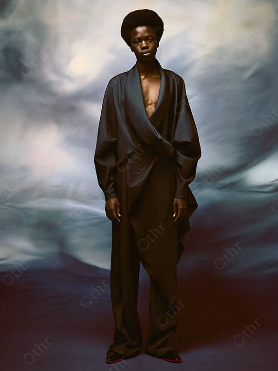 Full-Length Portrait of a Person in Flowing Dark Ensemble Against Cloud Backdrop