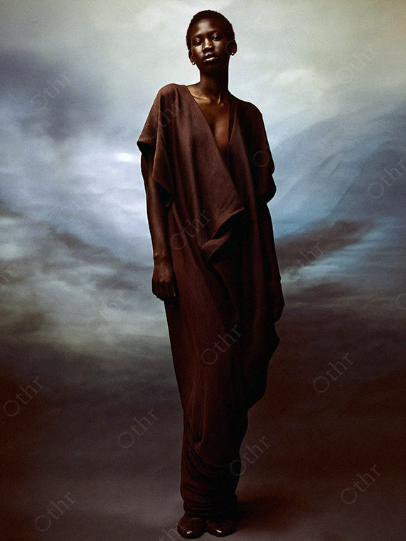 Full-Length Portrait of a Person in Flowing Brown Robe Against Cloud Backdrop