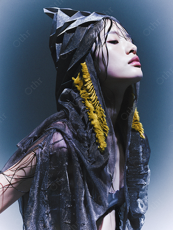 Fashion Portrait of a Person in Textured Hooded Garment With Yellow Fringe Detail