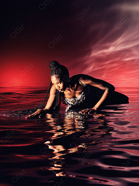 Fashion Portrait of a Person in Water With Braided Hair Against Red Sky Backdrop