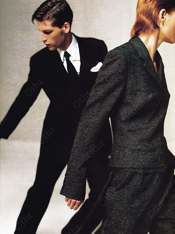 Editorial Fashion Portrait of Two Models in Dark Suits Against Neutral Background