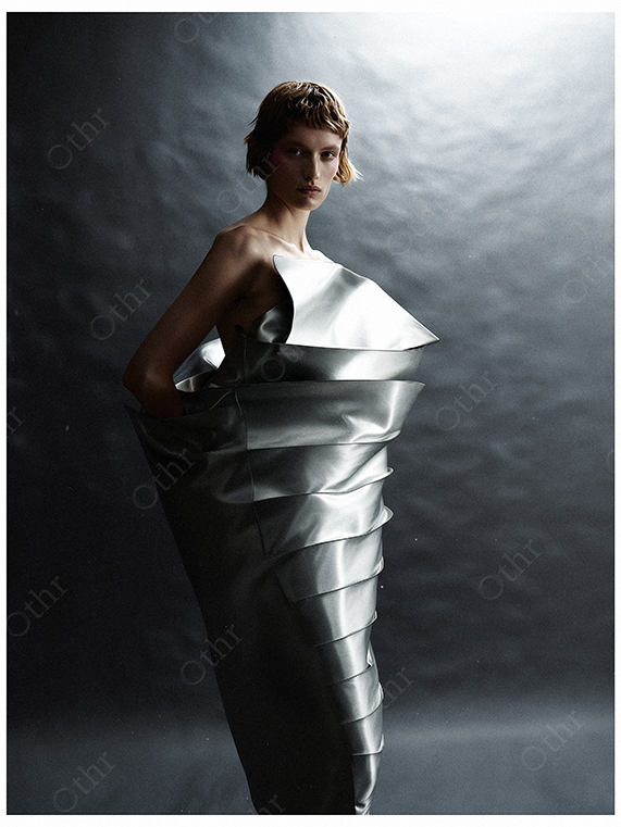 Fashion Portrait of a Person in Sculptural Metallic Gown Against Dark Studio Backdrop