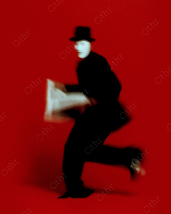 Blurred Figure in Black Suit and Hat Running With Newspaper on Red Background