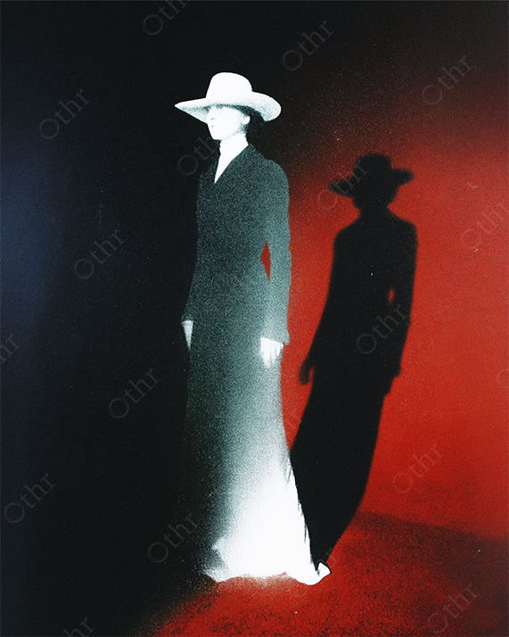 Figure in Long Coat and Wide-Brim Hat Casting Shadow on Red and Black Background