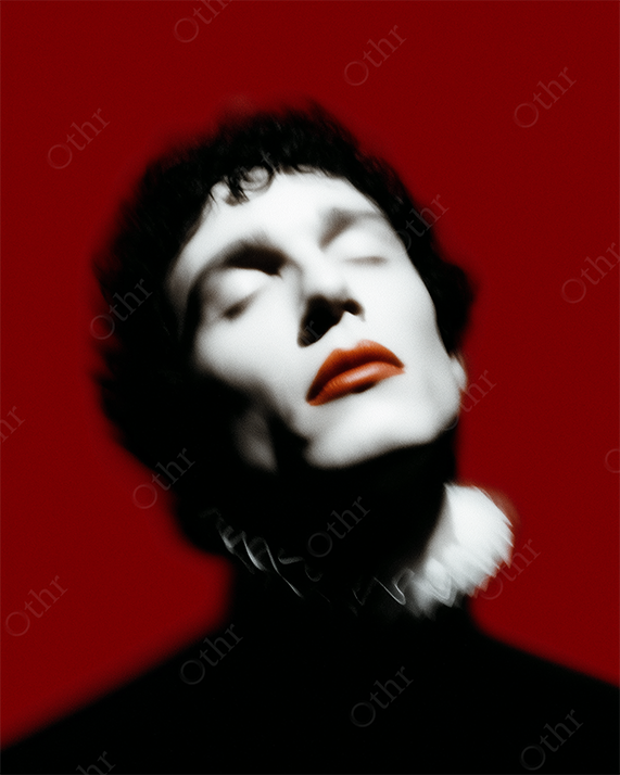 Blurred Close-Up Portrait of Person With Red Lips and White Collar Against Red Background