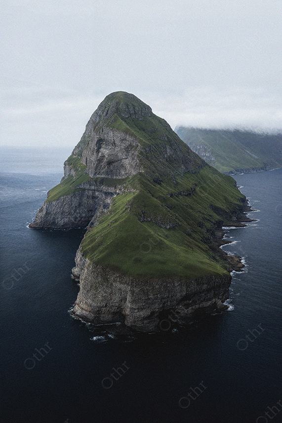 Steep Green Island Cliff Rising From Dark Blue Ocean