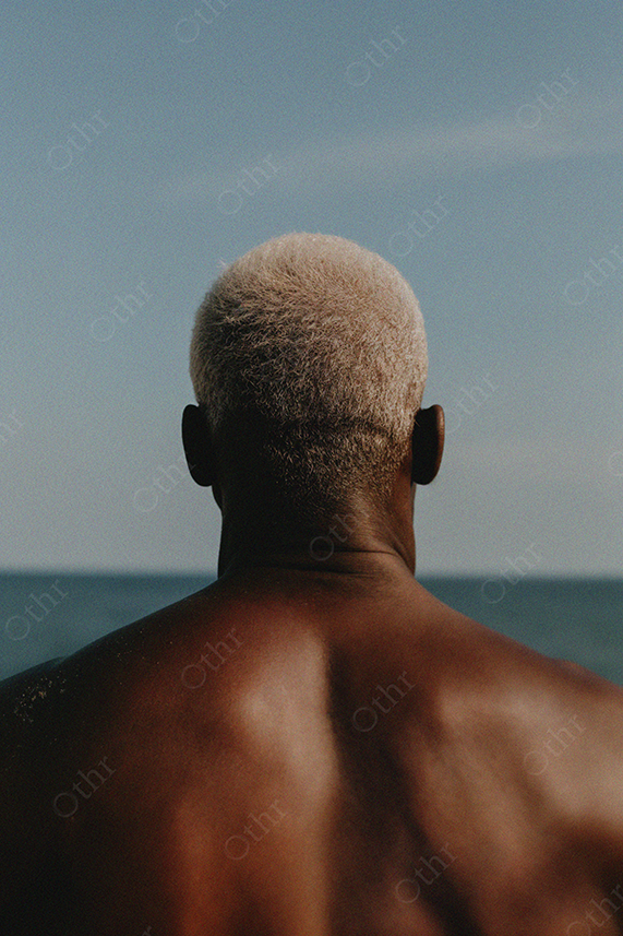 Rear View of Man With Blonde Hair Facing Ocean Horizon