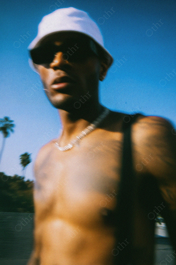 Blurred Portrait of Shirtless Man in Sunglasses and White Hat Outdoors