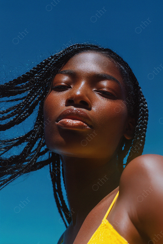 Portrait of Woman With Braided Hair and Yellow Top Against Blue Sky