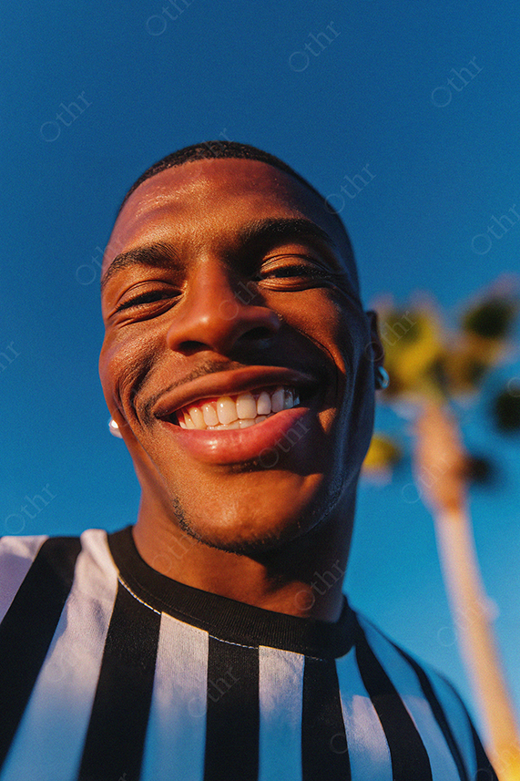 Close-Up of Smiling Man in Striped Shirt Under Blue Sky
