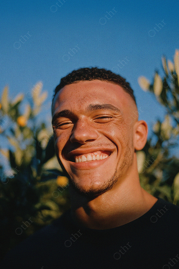 Portrait of Smiling Man Outdoors With Blue Sky and Greenery