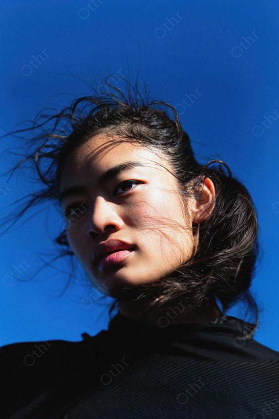 Portrait of Woman With Windblown Hair Against Clear Blue Sky