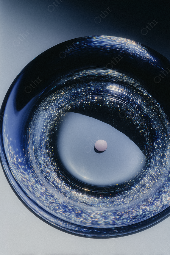 Pink pill on reflective glass ashtray.