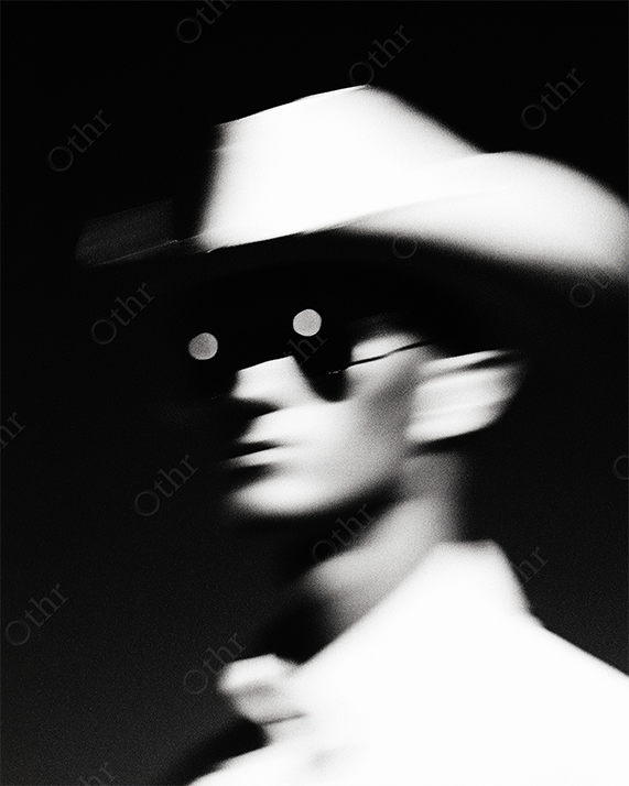 Out-of-Focus Figure in White Cowboy Hat and Sunglasses 