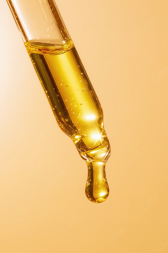 Close-Up of Skincare Serum Dropper with Golden Liquid on Amber Background