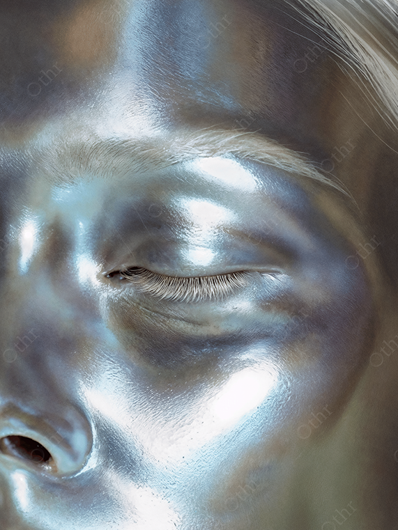Close up of a face coated in iridescent silver makeup with closed eyes — futuristic skin texture and luminous metallic sheen.