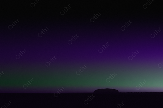 Uluru under a green-violet gradient sky.