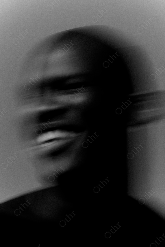 Blurred portrait of a smiling man in black and white.