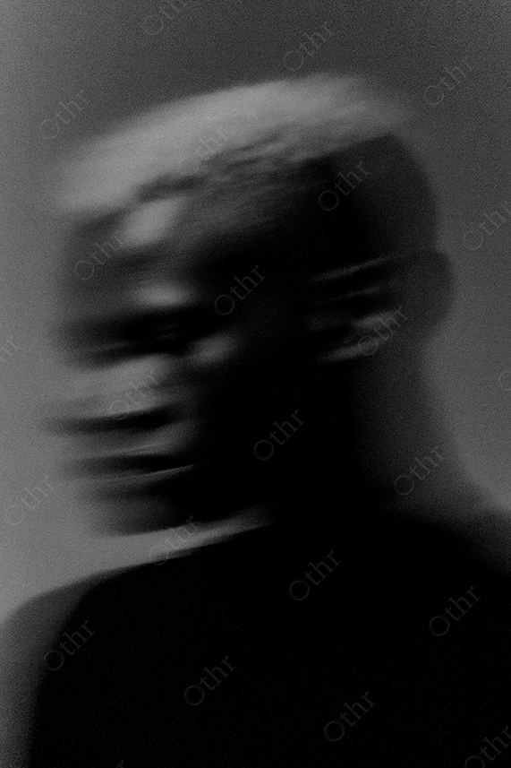 Blurred portrait of a man with blonde hair in black and white.