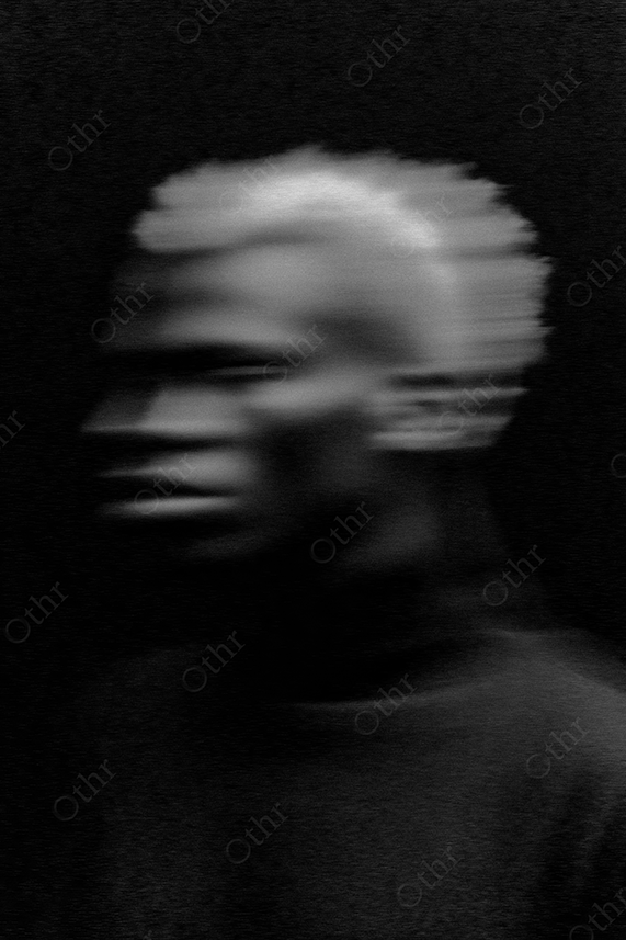 Blurred portrait of a man with blonde hair in black and white.