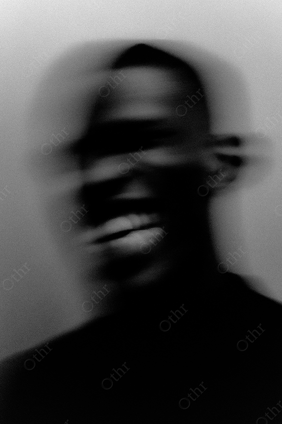 Blurred portrait of a man showing his teeth in black and white.