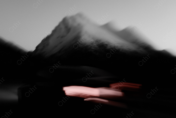 A car driving past a mountain with abstract motion blur and red lights.