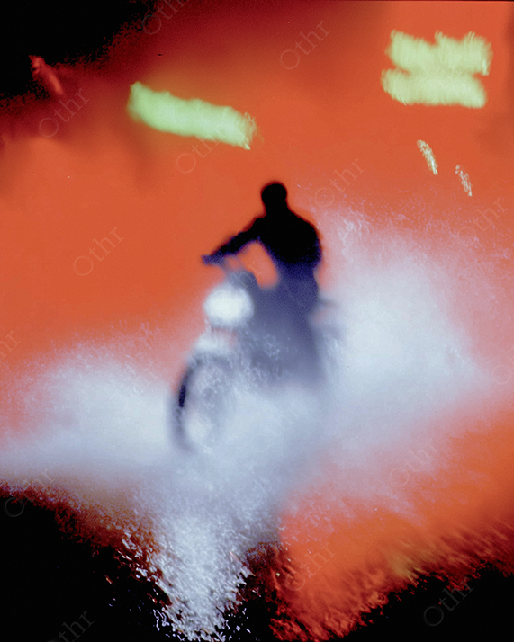 Motorcyclists driving on a hazy red street.