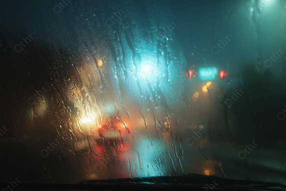 City street lights blurred through rainy window