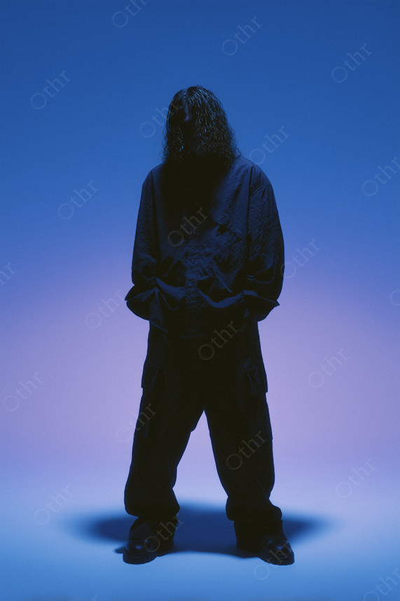Hooded figure under soft purple gradient light