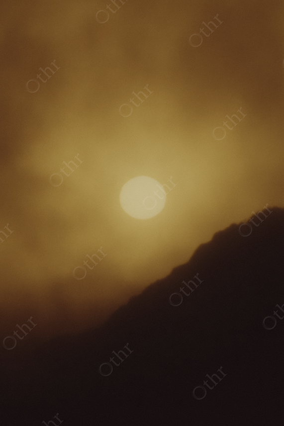 Hazy Sun Above Mountain Slope in Golden Light