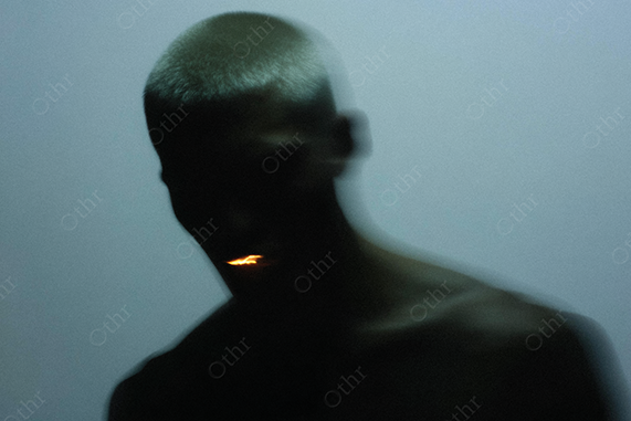 Shadowed Portrait of Person with Small Flame Emanating From Mouth