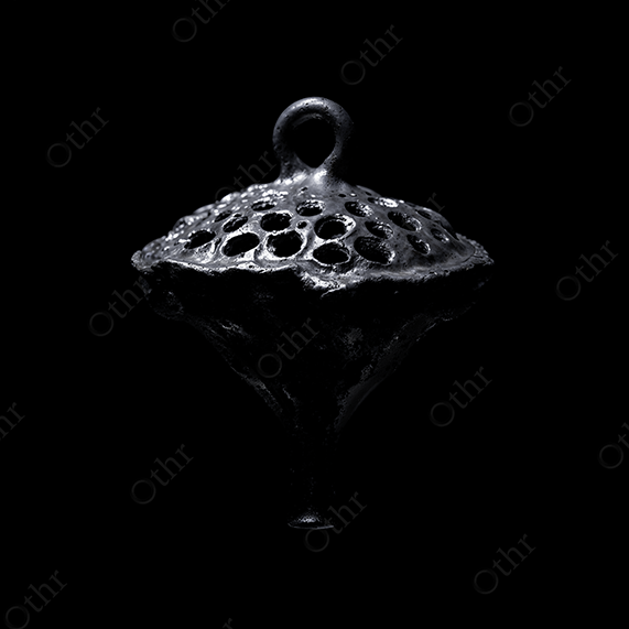 Metallic Lotus Pod Pendant With Circular Openings on Black Background – Still Life