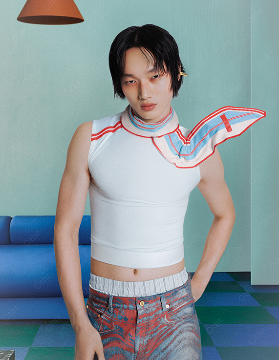 Portrait of Man in White Sleeveless Top and Patterned Jeans Standing in Retro Blue Interior