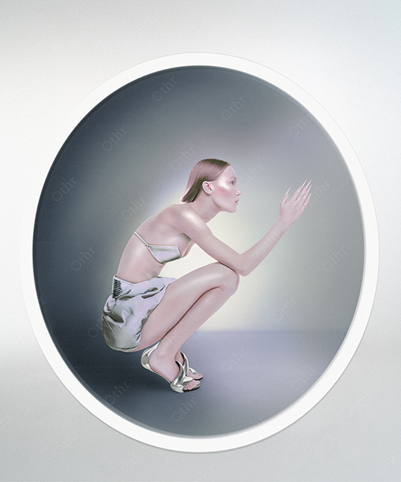 Woman in Metallic Silver Outfit Crouching in Circular Frame With Soft Gradient Light
