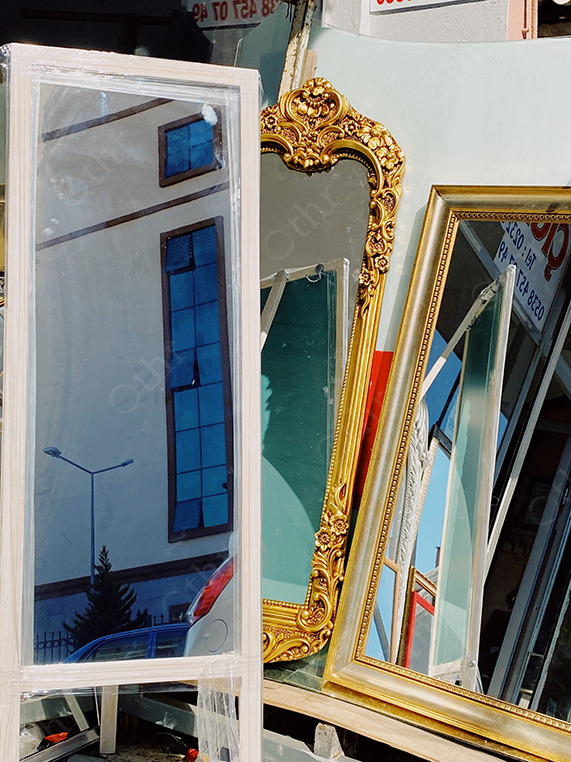 Assorted Framed Mirrors Displayed Outdoors Reflecting Building and Sky
