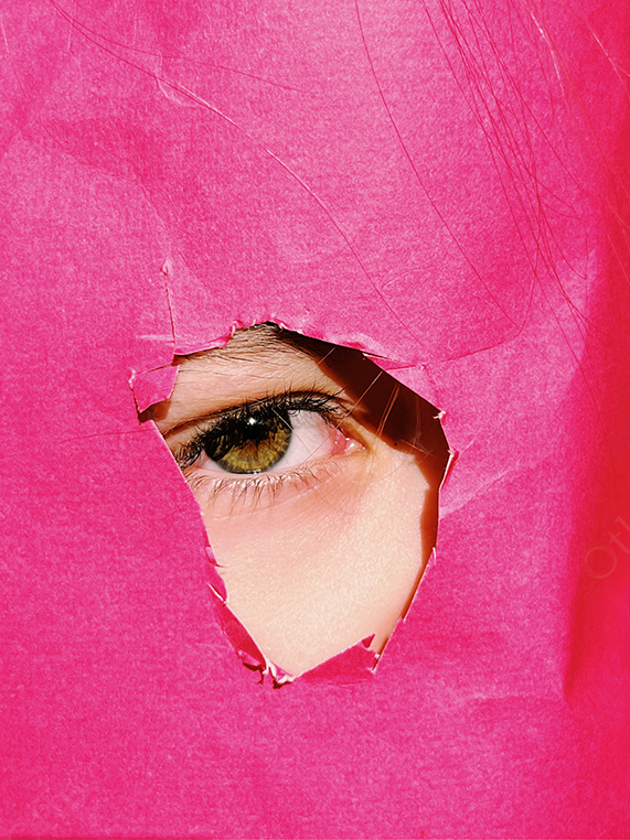 Close-Up of Eye Peeking Through Torn Pink Paper