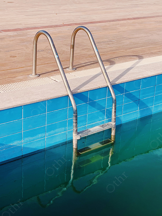 Metal Pool Ladder Emerging From Green Water Beside Blue Tiled Edge