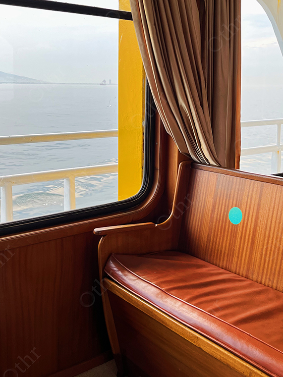 Leather Ferry Seat Beside Window Overlooking Calm Sea and Distant Shore