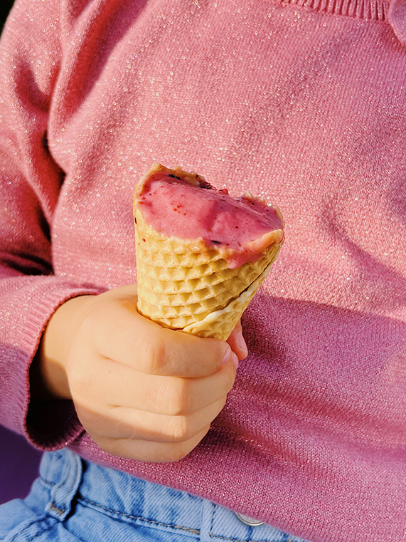 Child Holding Berry Ice Cream Cone While Wearing Pink Sweater