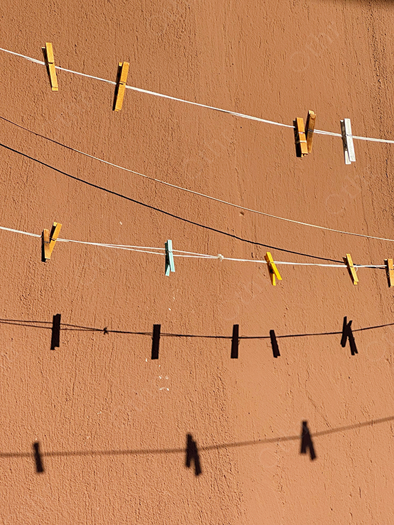 Coloured Cloth Pegs Casting Shadows on Brown Wall