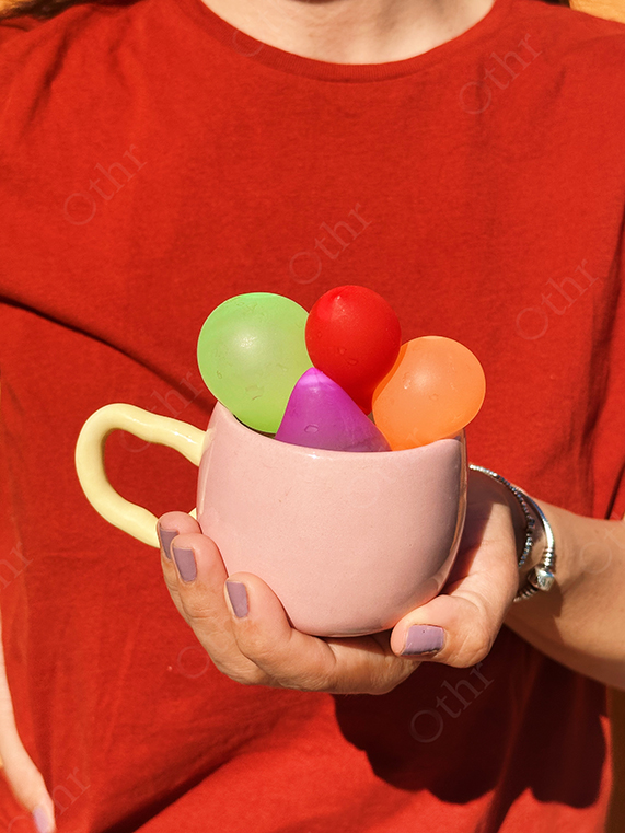 Person Holding Pink Mug Filled With Colourful Water Balloons